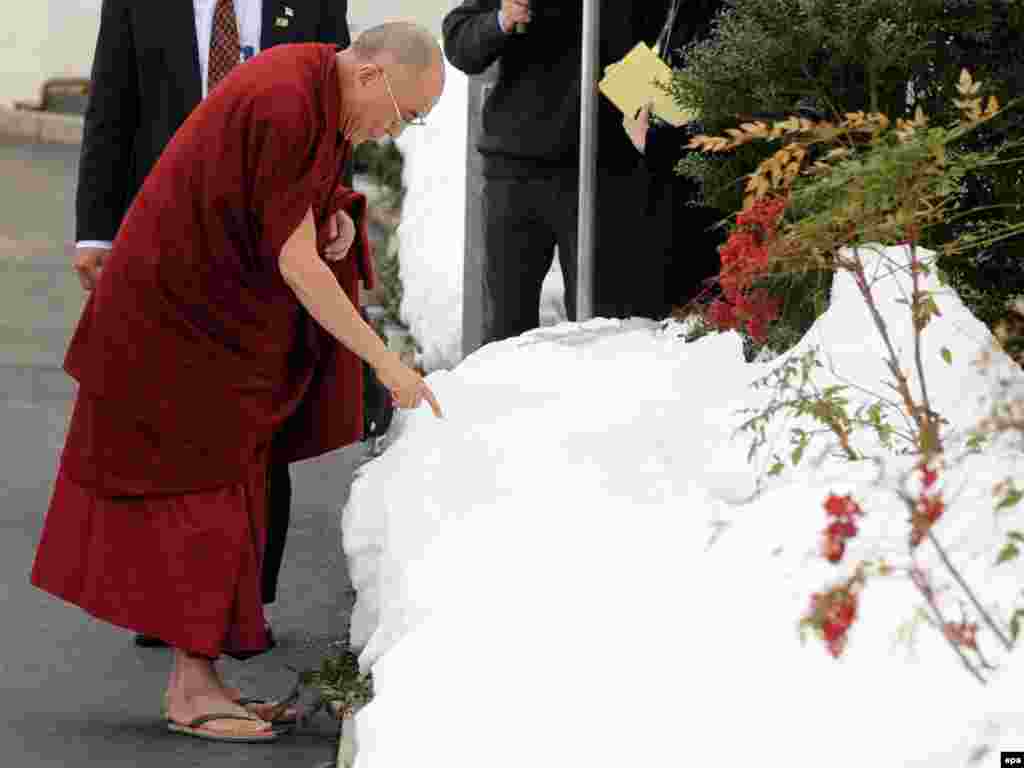 The Dalai Lama touches snow at the White House following a meeting with U.S. President Barack Obama. - Photo by Michael Reynolds for epa