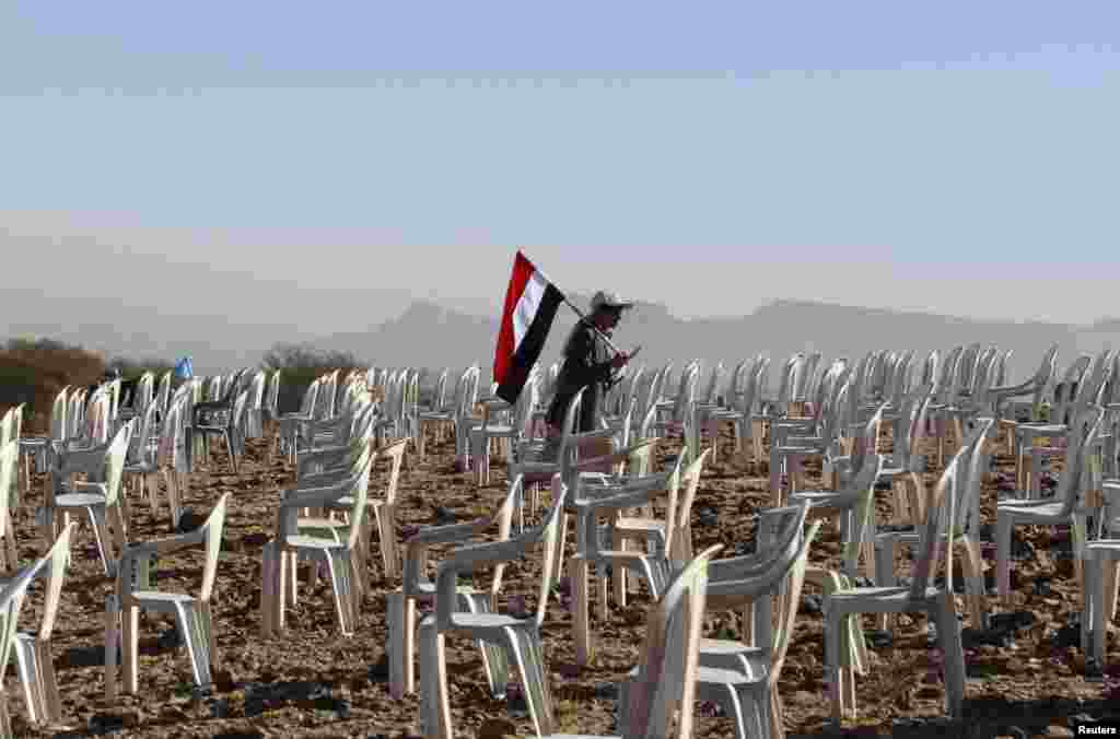 A Yemeni tribesman carries a national flag as he walks between chairs before a rally to commemorate the second anniversary of the uprising against former President Ali Abdullah Saleh in Bani Hushaish. (Reuters/Mohamed al-Sayaghi)