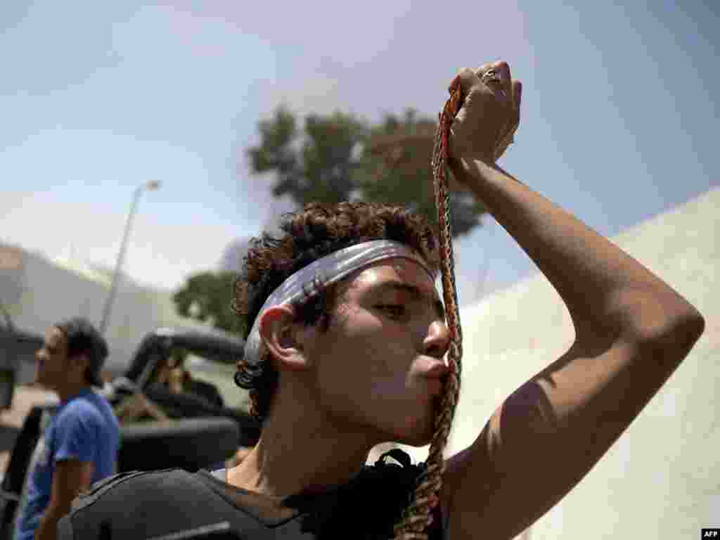 A Libyan rebel kisses a bullet belt at Muammar Qaddafi's Bab al-Aziziyah compound in Tripoli on August 25. Photo by Patrick Baz for AFP