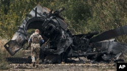 Украинский военнослужащий подходит к уничтоженному в бою российскому танку на освобожденной территории возле города Балаклеи в Харьковской области, 11 сентября 2022 года