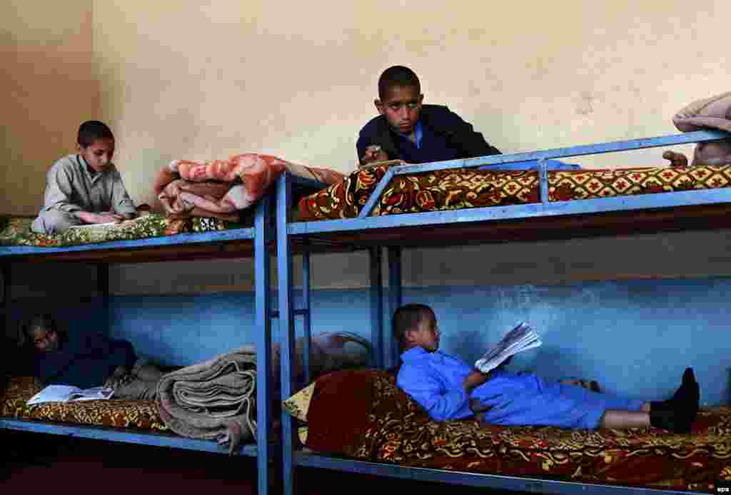 Afghan orphan children who lost their fathers to war, read books as they sit in their bunk beds at the Al-Nadwa orphanage in Jalalabad. (epa/Ghulamullah Habibi)