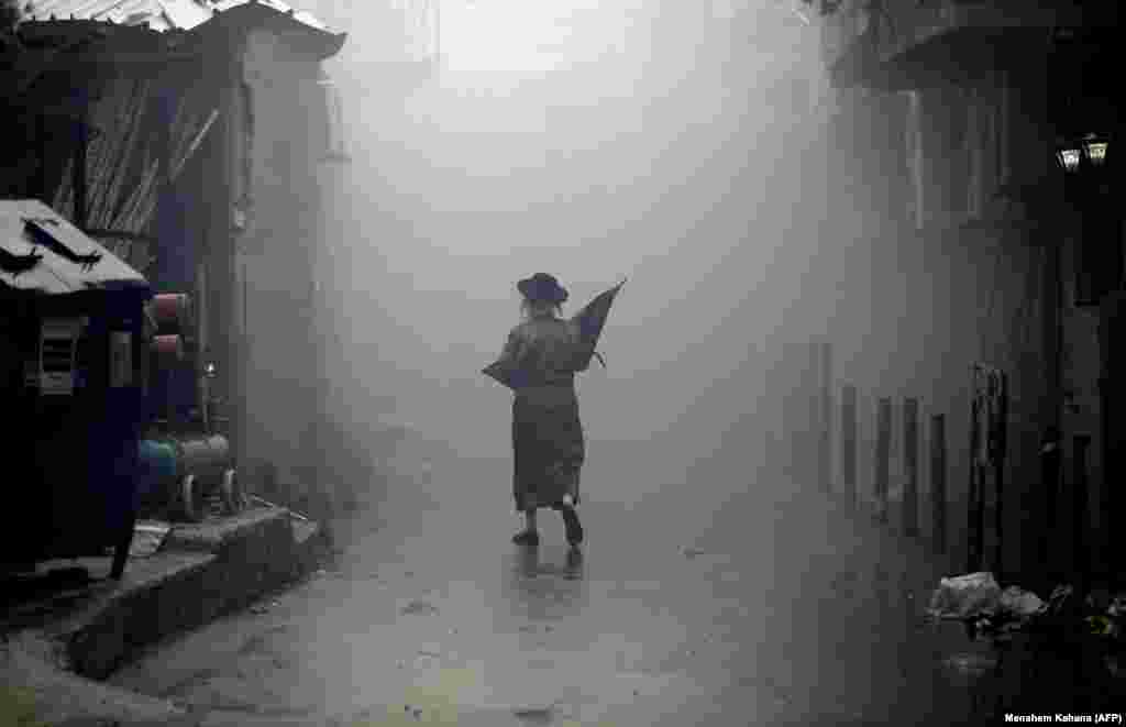 An Ultra-Orthodox Jewish man walks down a street through the smoke from burning leavened items during the Srefat Chametz ritual in Jerusalem on March 30. (AFP/Menahem Kahana)