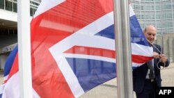 A member of the European Commission removes the British flag during a summit at EU headquarters in Brussels.