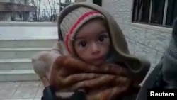 A toddler is held up to the camera in this still image taken from a video said to have been shot in Madaya on January 5.