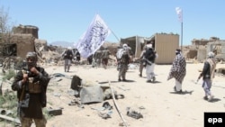 FILE: Suspected Taliban militants patrol after they reportedly took control of Ghazni's Waghaz district in May 2017. 