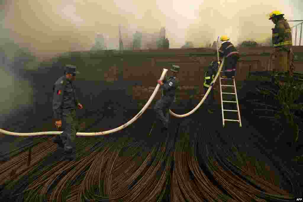 Afghan firefighters try to extinguish a fire at a wood market at Quwai Markaz in Kabul. (AFP/Wakil Kohsar)