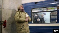 Sankt Peterburgdaky metronyň gapdalyna gül goýan zenan.