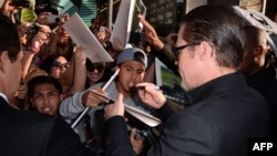 Actor Brad Pitt (right) signs autographs as he attends the world premiere of Disney's "Maleficent" at the El Capitan Theatre in Hollywood on May 28.