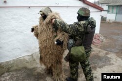 A Ukrainian serviceman assists another soldier with camouflage in a village near Mariupol on January 26.