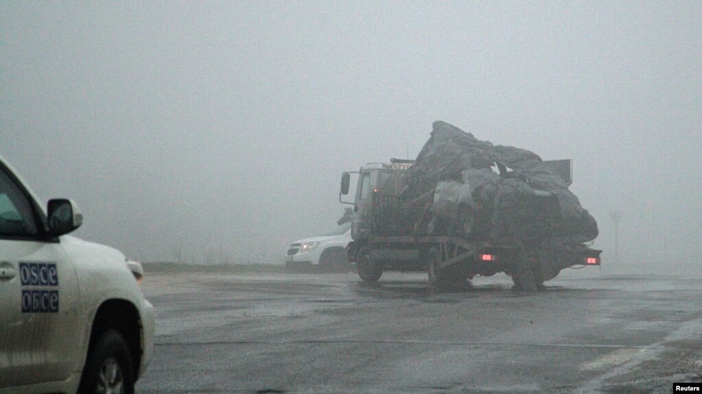 The damaged vehicle that drove over a land mine while transporting members of the OSCE, killing one and injuring two, is moved from the scene of the tragic incident on April 23.