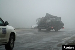 The damaged vehicle that drove over a land mine while transporting members of the OSCE, killing one and injuring two, is moved from the scene of the tragic incident on April 23.