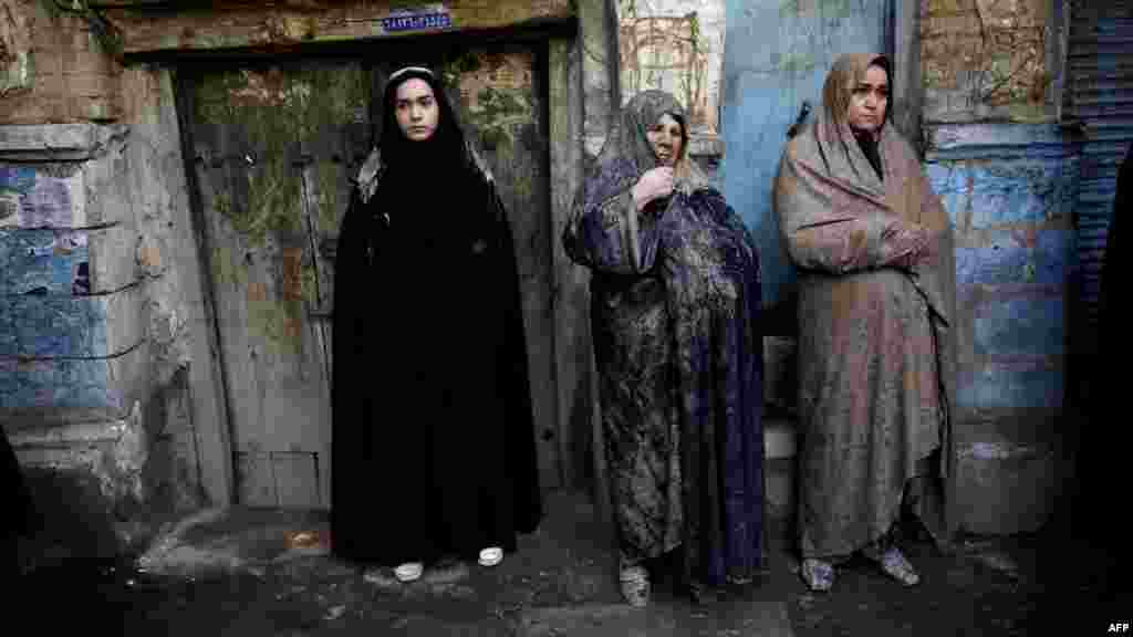 Shi&#39;ite Muslim women with mud on their veils watch the &quot;Kharrah Mali&quot; (Mud Rubbing) ritual to mark the Ashura religious ceremony in the city of Khorramabad, Iran. (AFP/Behrouz Mehri)