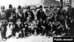 Grupa četnika sa nemačkim vojnicima u nepoznatom selu u Srbiji, fotografisano u periodu od 1941. do 1945.