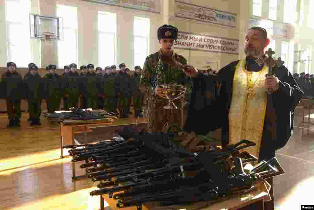 An Orthodox priest blesses rifles during a ceremony where new recruits receive their weapons at a military base of the Belarusian Interior Ministry in Minsk. (Reuters/Vasily Fedosenko)