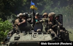 Украинские военнослужащие едут на бронетранспортере по дороге в Донецкой области, 7 июля 2022 года