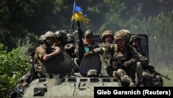 Ukrán katonák egy páncélozott szállítójárművön (APC) ülnek Donyeck térségében 2022. július 7-én 