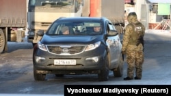 A Ukrainian border guard checks a car with a Russian number plate at a crossing point on the border between Russia and Ukraine in Kharkiv on November 30.