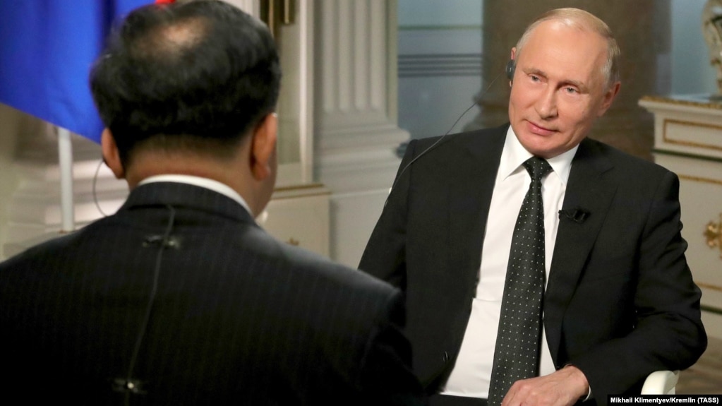 Russian President Vladimir Putin listens in an interview with China Media Group President Shen Haixiong.