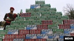 An Iranian security officer poses with confiscated alcohol. Iranian officials estimate that up to 80 million liters of alcohol worth $730 million are smuggled into the country every year. (file photo)