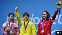 Қазақстандық ауыр атлет Майя Манеза (ортада) олимпиада тұғырында алтын алып тұр. Лондон, 31 шілде 2012 жыл.