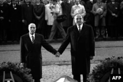 Президент Франції Франсуа Міттеран і канцлер Німеччини Гельмут Коль тримаються за руки на знак примирення між Францією та Німеччиною під час церемонії вшанування пам’яті жертв Другої світової війни, 22 вересня 1984 року