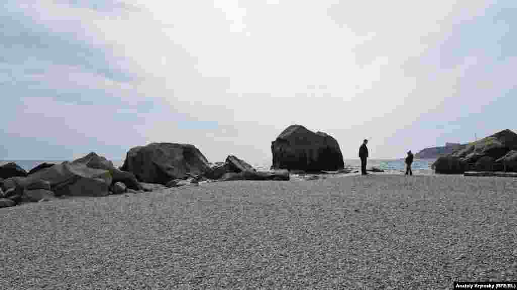 Детский пляж курортного города в обрамлении каменных глыб