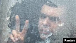 An opposition supporter, who is being held for demonstrating in a protest, flashes a victory sign from a police bus near a detention center in Minsk.