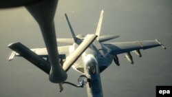 Un avion de tip F-18E Super Hornet al marinei militare americane alimentat cu carburant de un aparat KC-135 Stratotanker deasupra nordului Irakului după ce a efectuat un atac în Siria northern Iraq after conducting air strikes in Syria, 23 September 2014