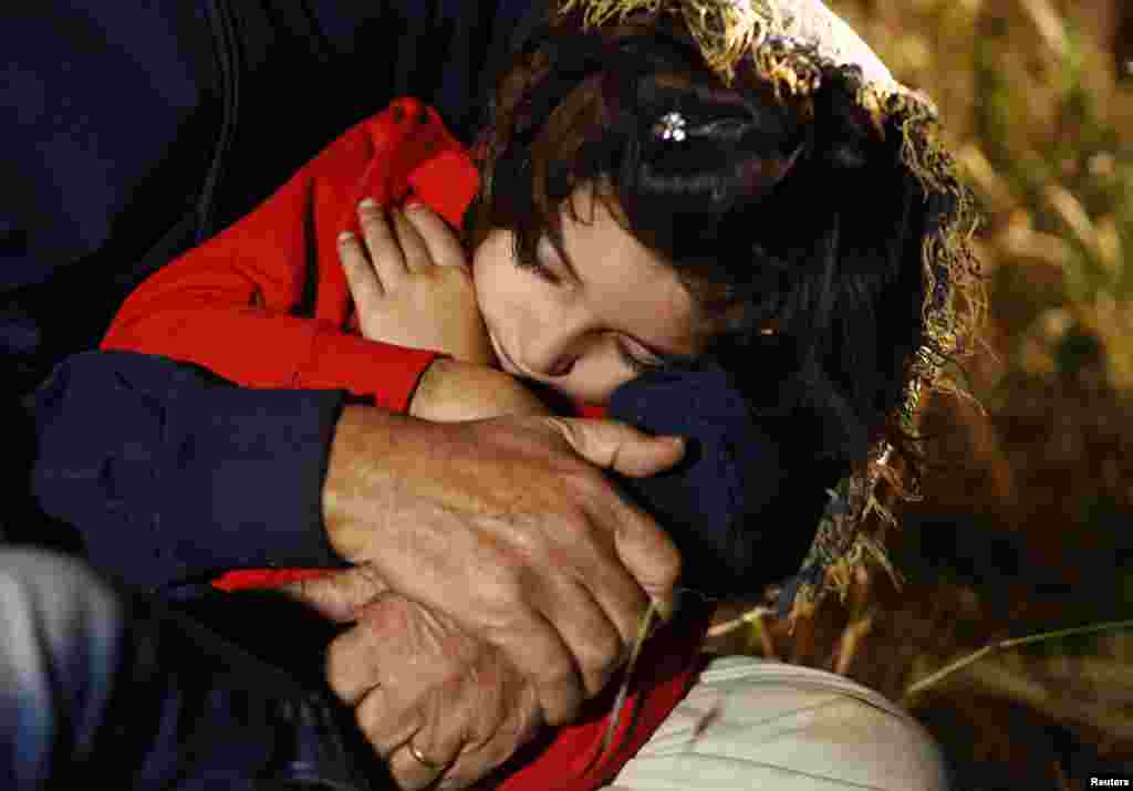 A young Syrian girl sleeps in the arms of a relative after her family was after apprehended by Serbian border police. Most illegal migrants see Serbia as the gateway to Hungary and the borderless Schengen zone. 