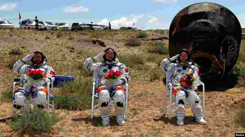 Astronauts Jing Haipeng (center), Liu Wang (left), and Liu Yang salute in front of the reentry capsule of the "Shenzhou 9" spacecraft in Siziwang Banner, in China's Inner Mongolia Autonomous Region. (Reuters/Xinhua/Wang Jianmin)