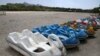 In this July 10, 2018 photo, a row of bird-shaped paddle boats sit on the parched Zayandeh Rood riverbed, in Isfahan, Iran.