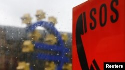 A sculpture of the euro's logo is seen behind an emergency telephone in Frankfurt.