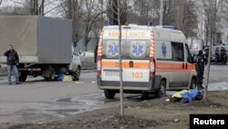 The bodies of two of the victims of the February 22 bombing in Kharkiv are covered by Ukrainian flags at the scene of the attack.