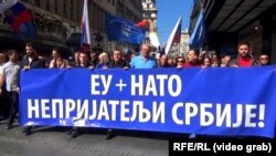 Far-right protesters in Belgrade commemorate the NATO strikes in Serbia, walking behind a sign that reads "EU + NATO, Our Enemies," on March 24.