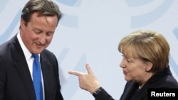 German Chancellor Angela Merkel (right) chats with Britain's Prime Minister David Cameron during a news conference after talks in Berlin on November 18.