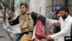 A police officer carries the body of a wounded worshiper at one of two mosques stormed by gunmen in Lahore on May 28.