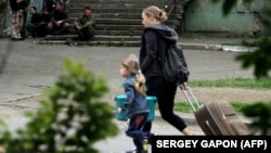 Местные жители в квартале, расположенном вплотную к Луганской погранзаставе, 2 июня 2014 года. На лестнице дальше сидят члены вооруженных формирований