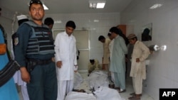 Police and civilians gather at a hospital morgue holding the bodies of suicide-bombing victims in Khost on June 20.