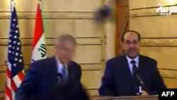 Президент США Джордж Буш уворачивается от ботинка, справа — иракский премьер-министр Нури аль-Малики. Ирак, 14 декабря 2008 года. 