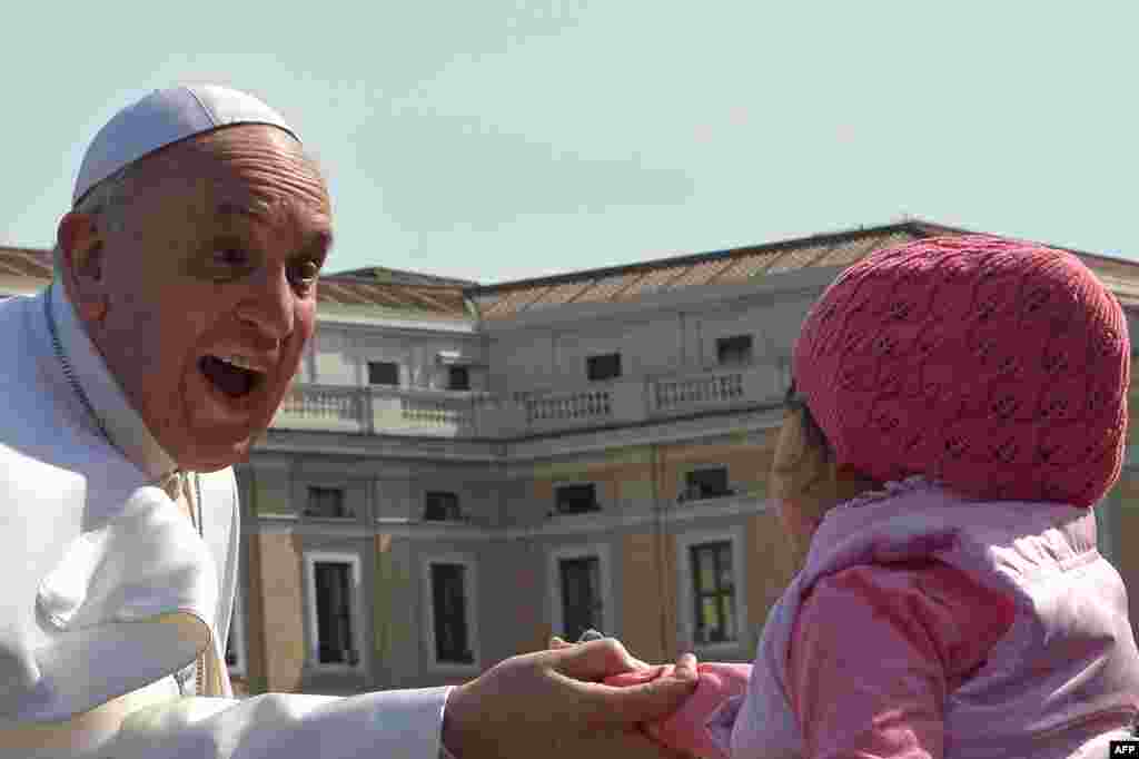 Pope Francis greets a young girl as he arrives for his weekly general audience at St. Peter's Square at the Vatican. (AFP/Alberto Pizzoli)