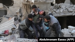 Emergency workers rescue a child following a reported regime air strike in the rebel-held Syrian town of Hamouria in the besieged Eastern Ghouta region on February 21.