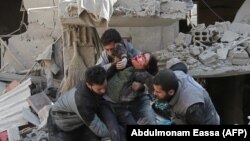 Сирийцы спасают ребенка после воздушного удара сил Асада в повстанческом городе Хамурия, в осажденном регионе Восточная Гута на окраине Дамаска, 21 февраля 2018 года 