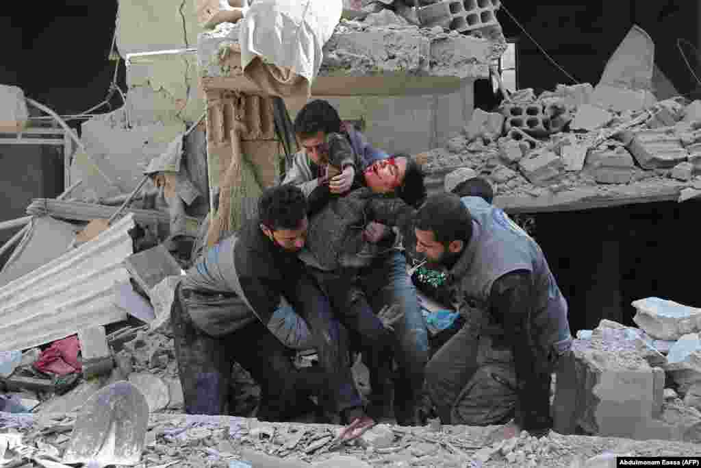 Syrians rescue a child following a reported regime air strike in the rebel-held town of Hamouria, in the besieged eastern Ghouta region on the outskirts of Damascus on February 21. (AFP/Abdulmonam Eassa)