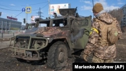 Український військовослужбовець оглядає знищений російський піхотний броньований автомобіль «Тигр» після бою в Харкові, 27 лютого 2022 року