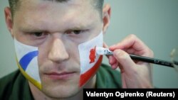 An officer with the Ukrainian State Border Guard Service has his face painted in the colors of both Liverpool and Real Madrid as he prepares to meet soccer fans at the Boryspil International Airport outside Kyiv on May 25. 