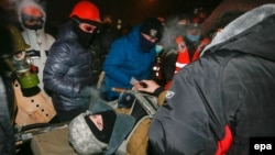Дәрігерлер қақтығыстарда зардап шеккен адамға көмек көрсетіп жатыр. Киев, 19 қаңтар 2014 жыл.