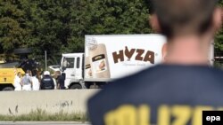 Австриский полицеский стоит на фоне грузовика-рефрижератора, в котором были обнаружены тела мертвых нелегальных мигрантов. 27 августа 2015 года.