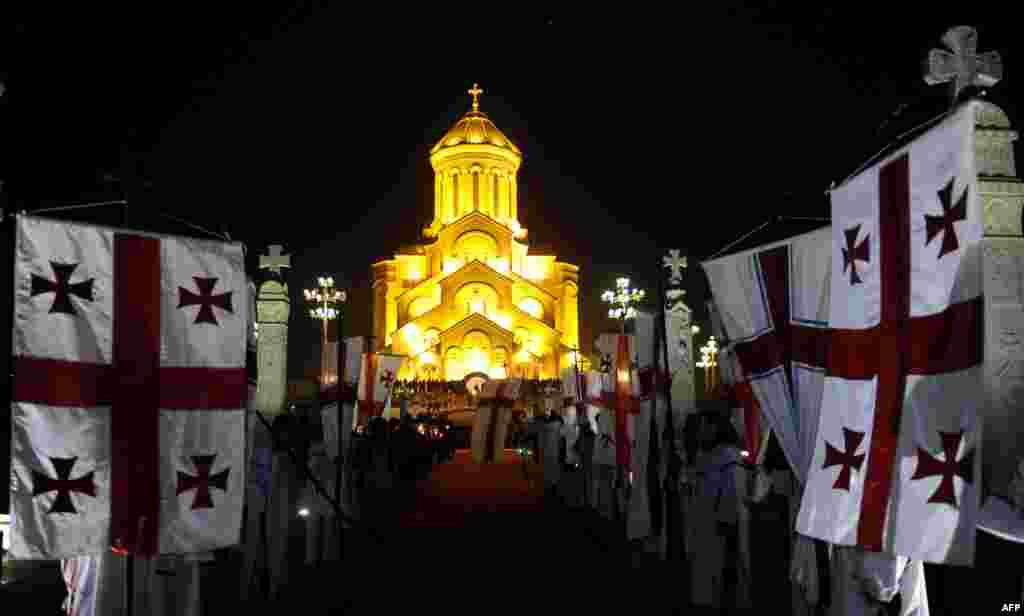 Georgian flags fly outside the Trinity Cathedral during Christmas Mass in Tbilisi.