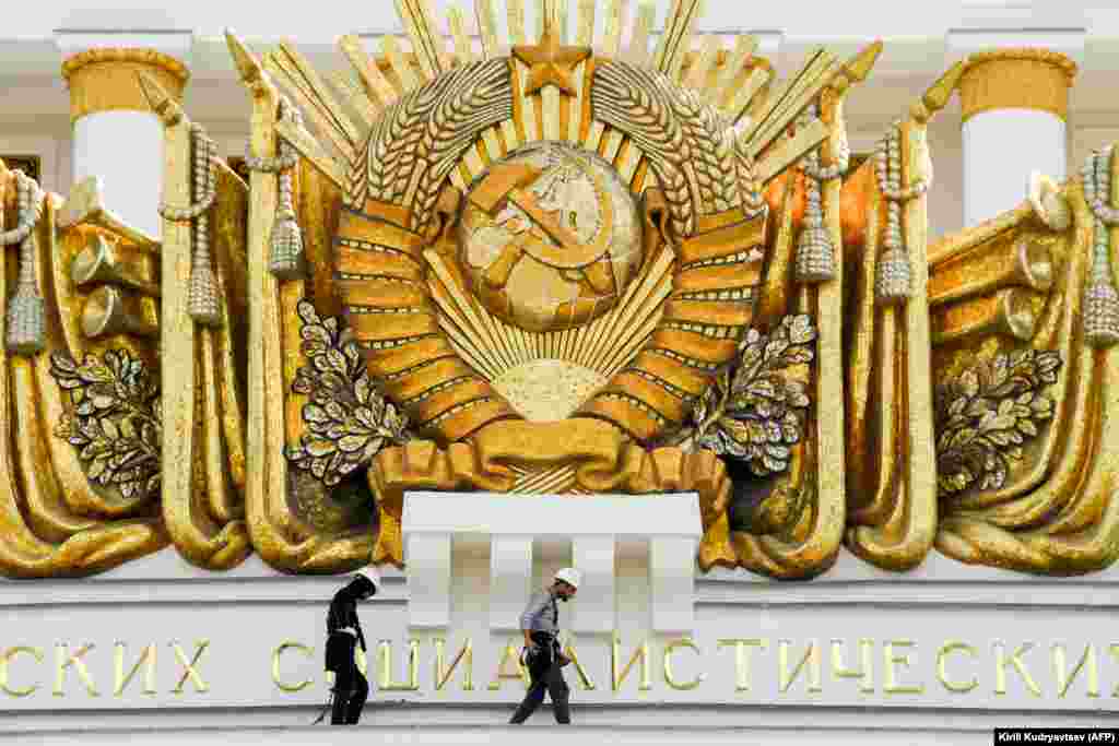 Workers fix a cornice close to a Soviet emblem at an exhibition center and amusement park in Moscow. (AFP/Kirill Kudryavtsev)
