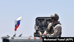 SYRIA -- A Russian soldier guards a checkpoint as displaced Syrians from the Daraa province come back to their hometown in Bosra, southwestern Syria, July 11, 2018